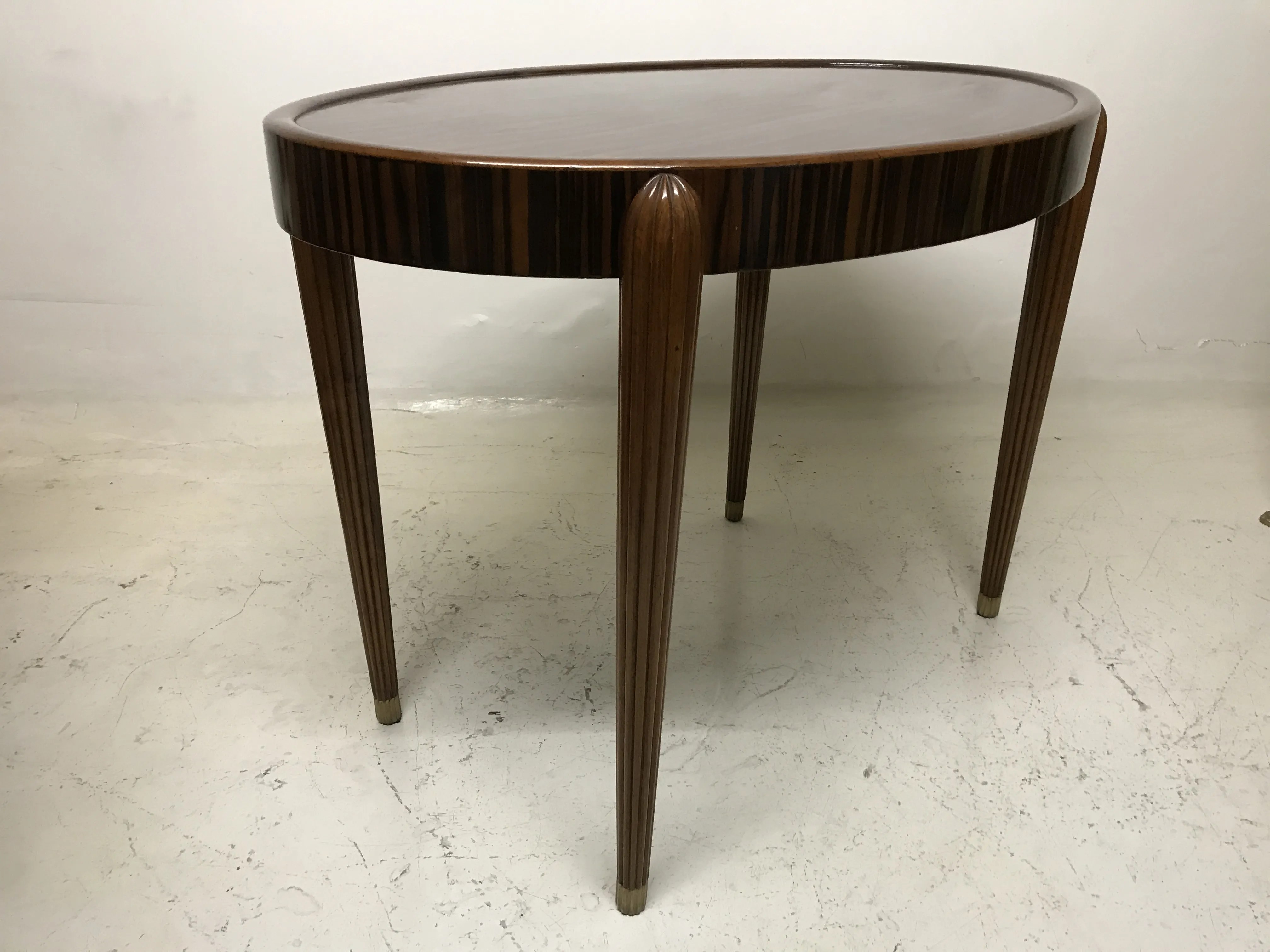 Round antique small table with elegant legs in a neutral setting.