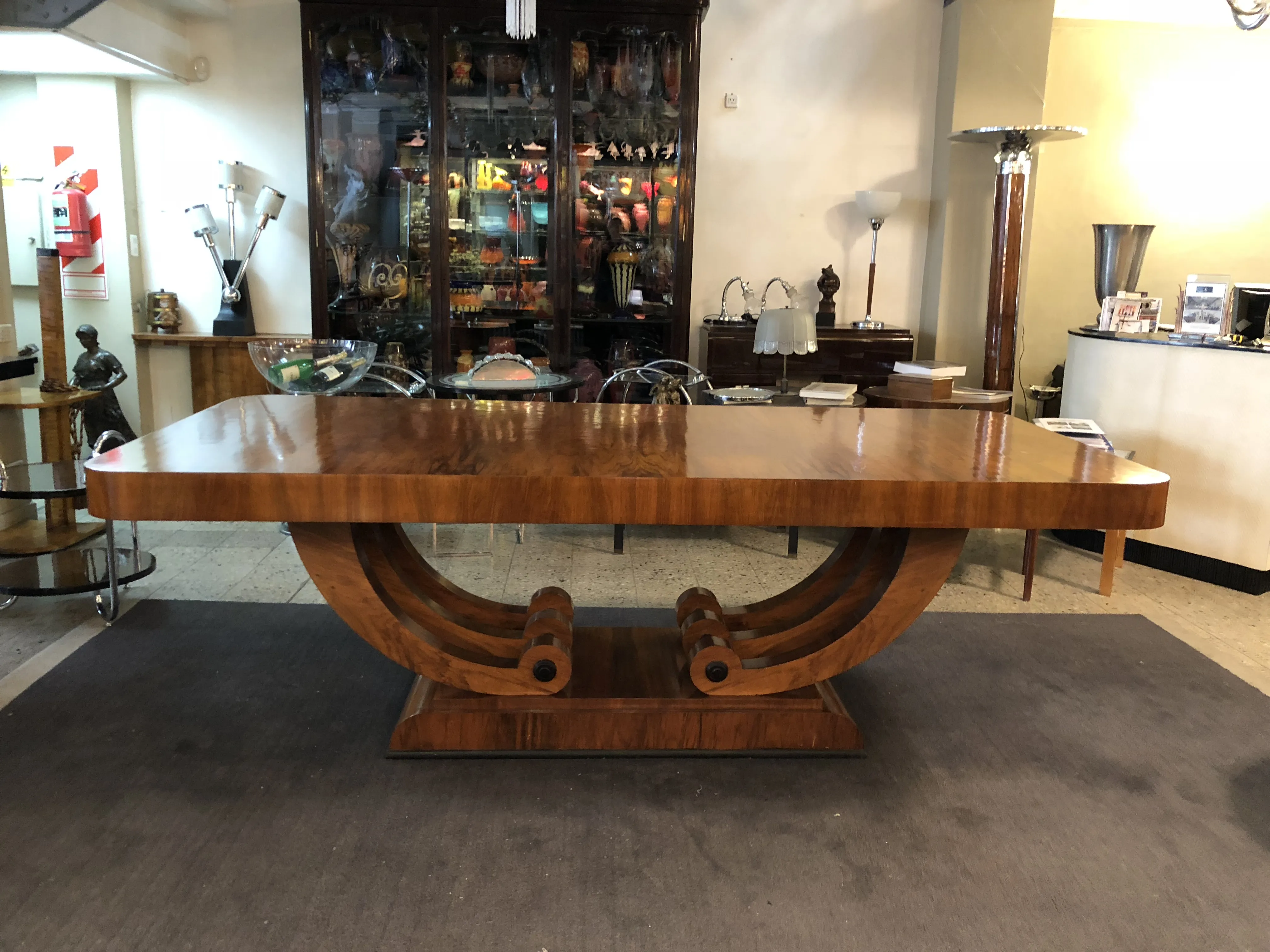 Antique Art Deco dining table for 10 people, featuring a unique base and a glossy finish, in an elegant setting.