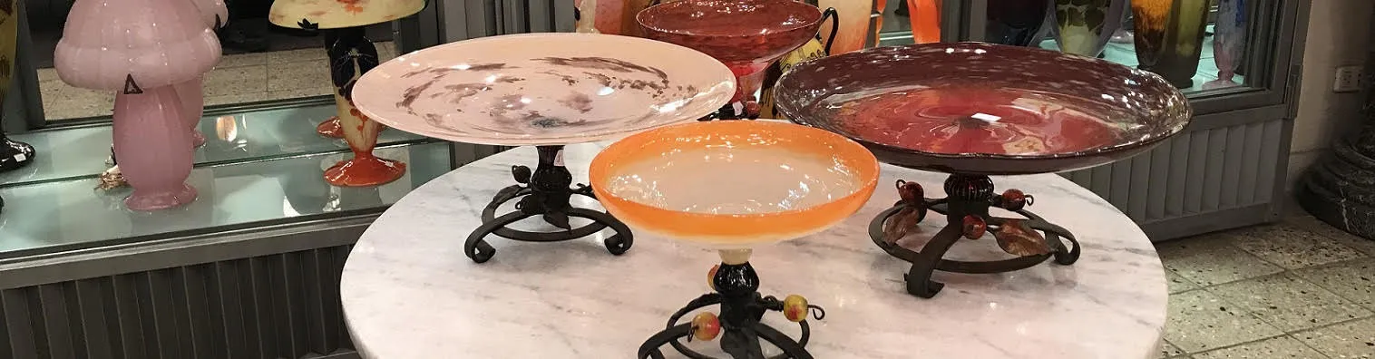 Vitrine com pratos de vidro em estilos variados e cores quentes.