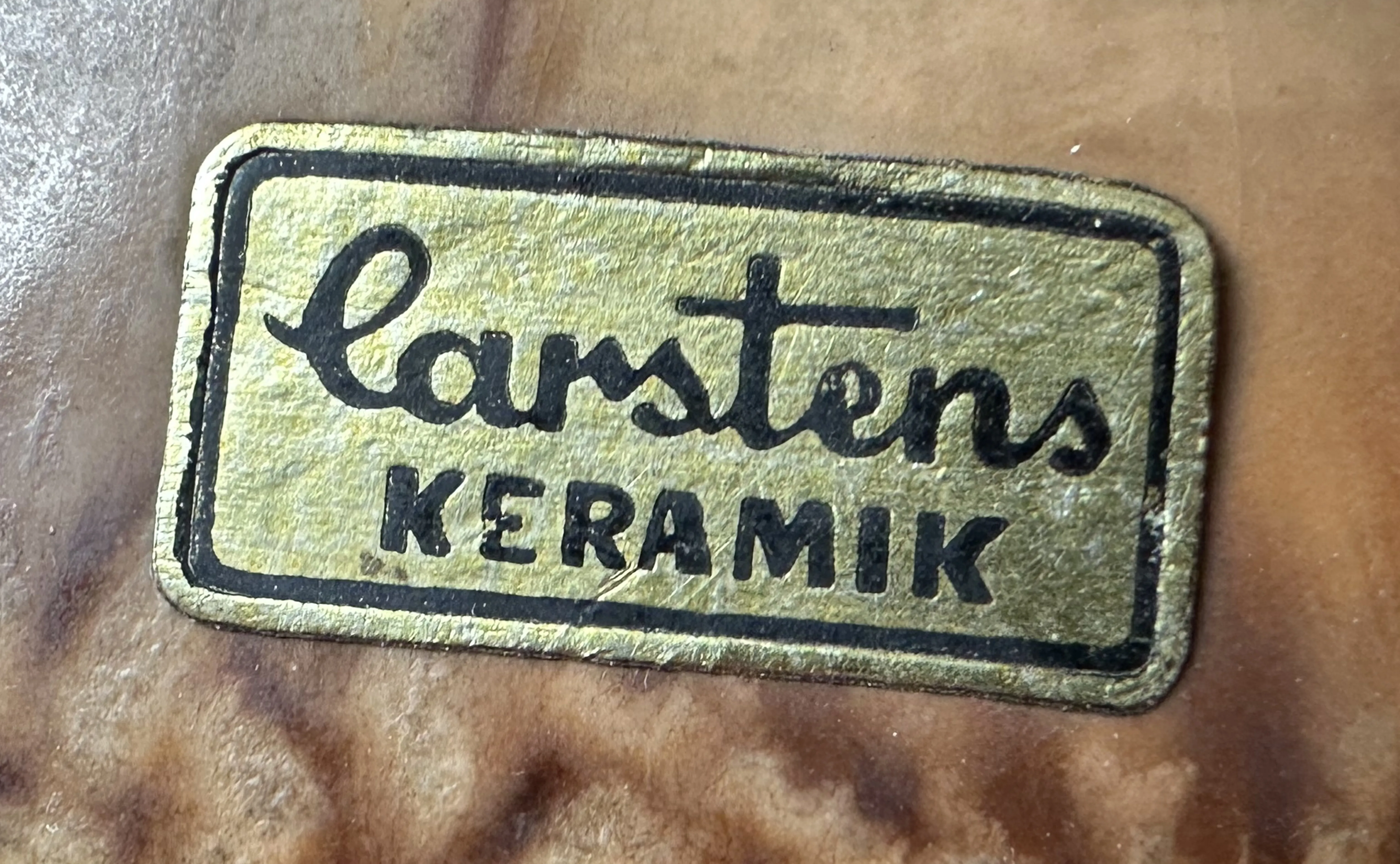 selo antigo com a marca Carstens Keramik em ouro e preto sobre fundo marrom