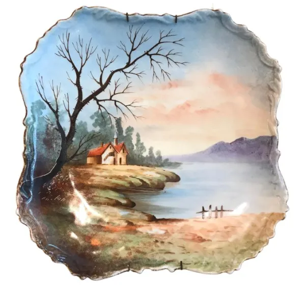 Antique ceramic plate featuring a painted landscape with a house and tree.