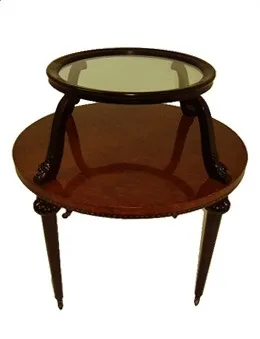 Antique small table with round glass surface and carved legs in a cozy setting.