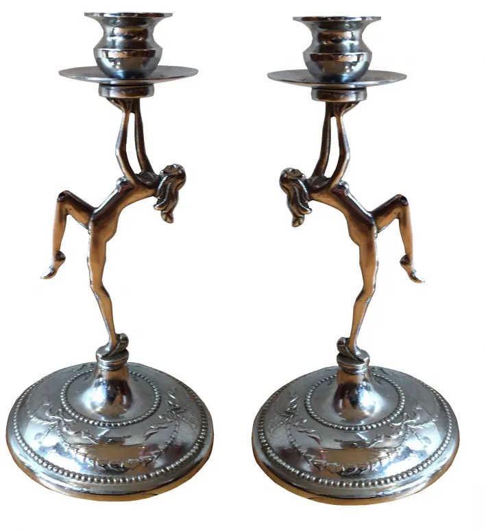 two antique candle holders with artistic figures at the base