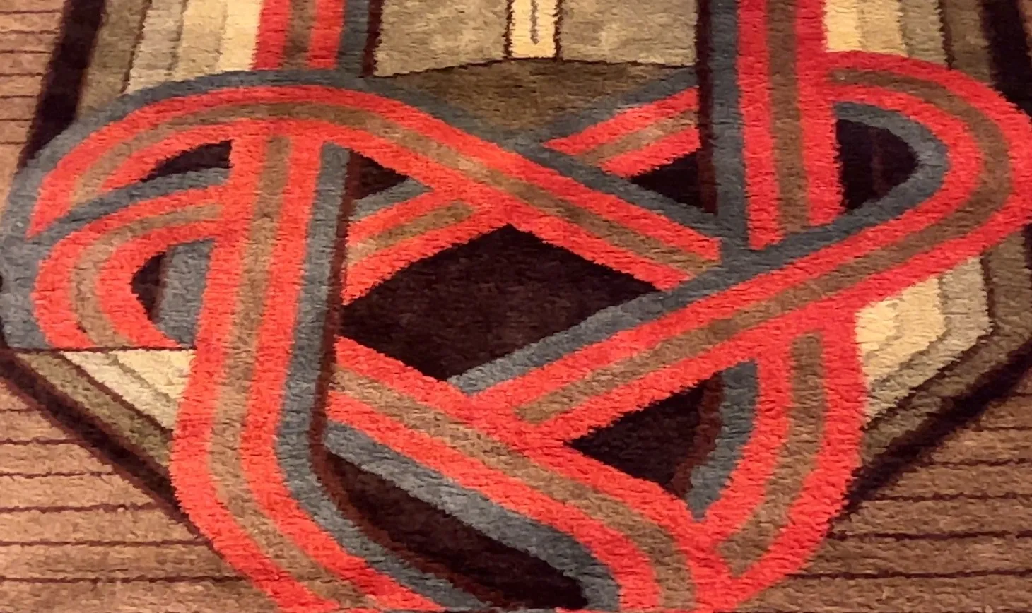 Decorative rug with intertwined patterns in red and blue tones