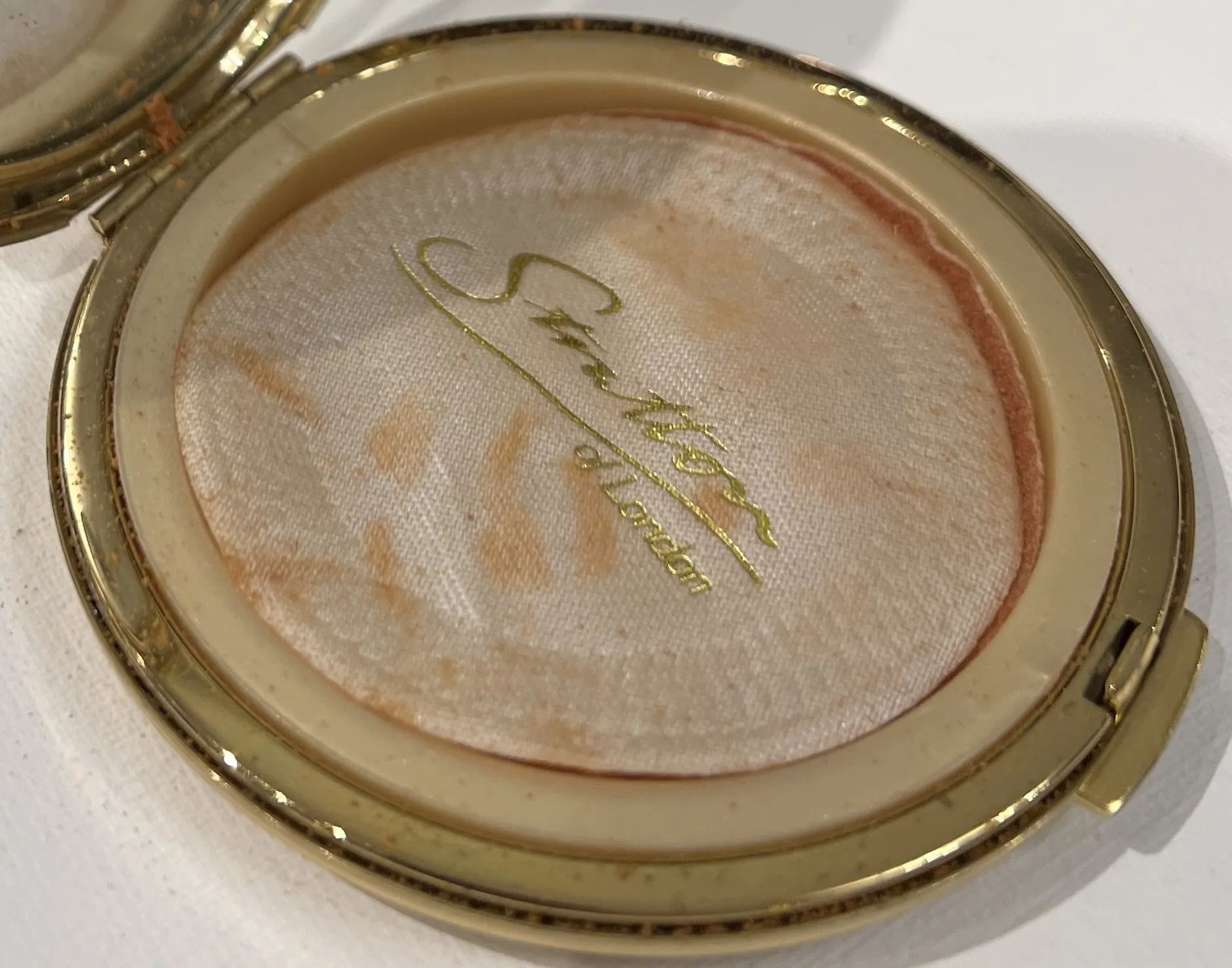 Antique makeup seal by Stratton of London with golden accents.