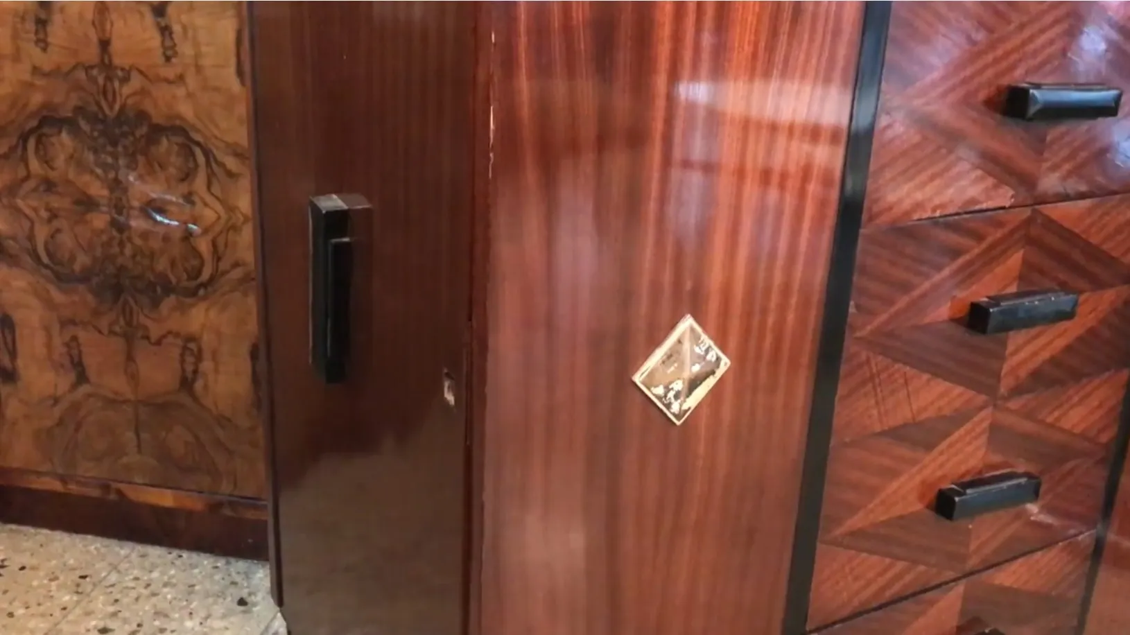 Gaveteira antiga com detalhes em marrom e preto, fundo decorativo.