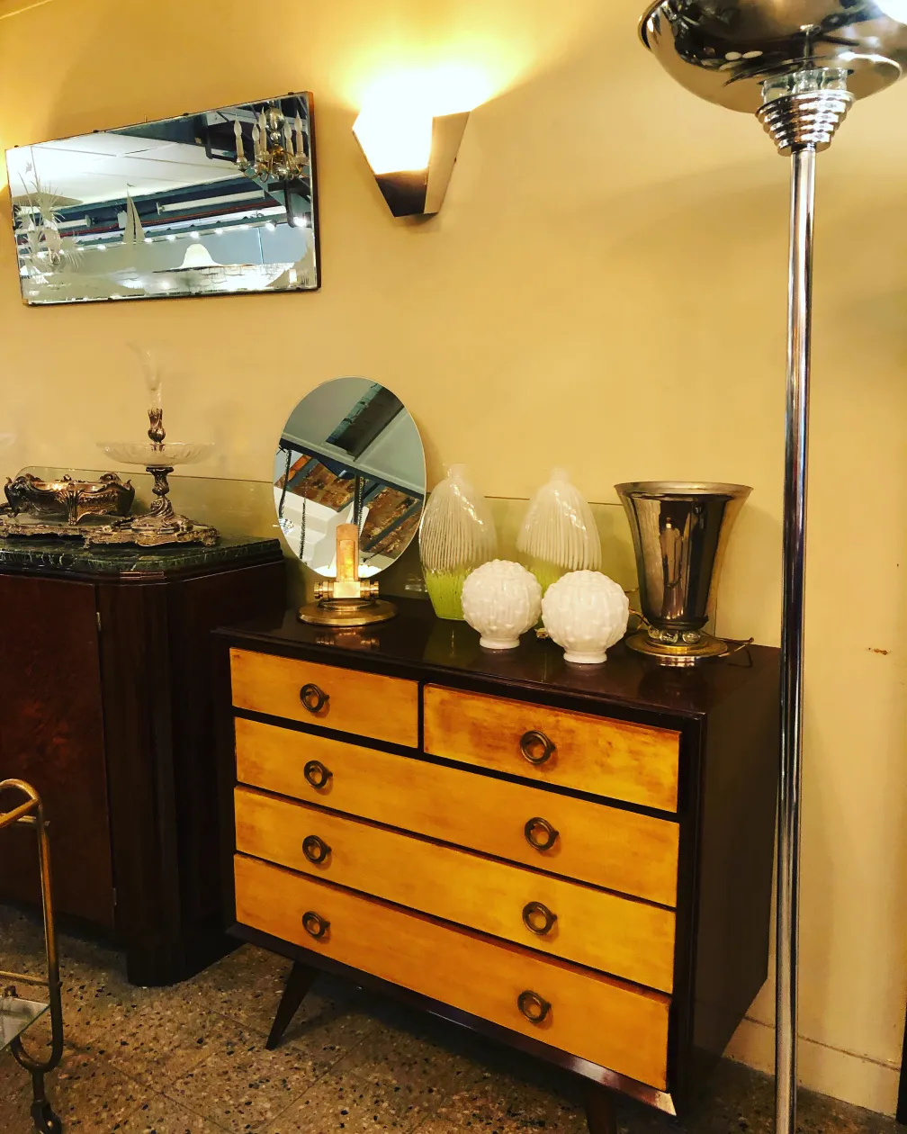 Cómoda antigua de madera con acabados en tonos amarillos, decorada con objetos de cristal y metal.