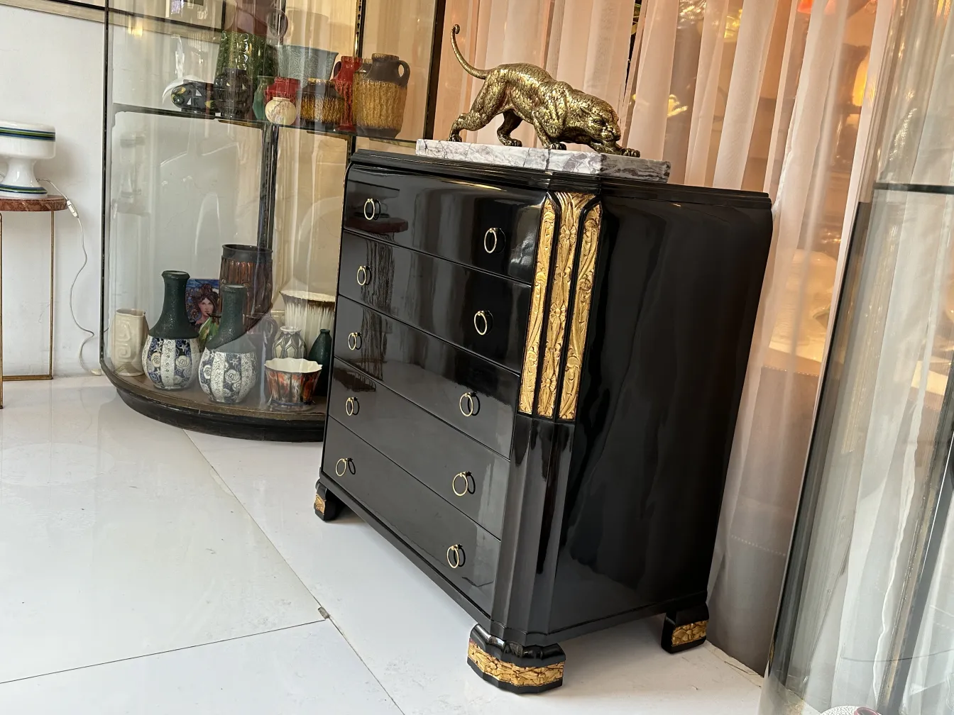 Cómoda antigua negra con detalles dorados en un ambiente elegante.