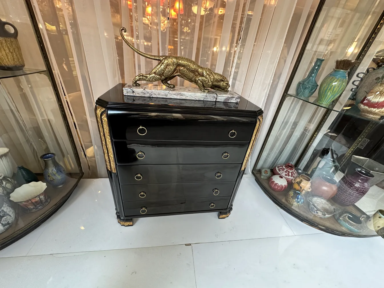 Cómoda negra con detalles dorados, decorada con una estatua de pantera.