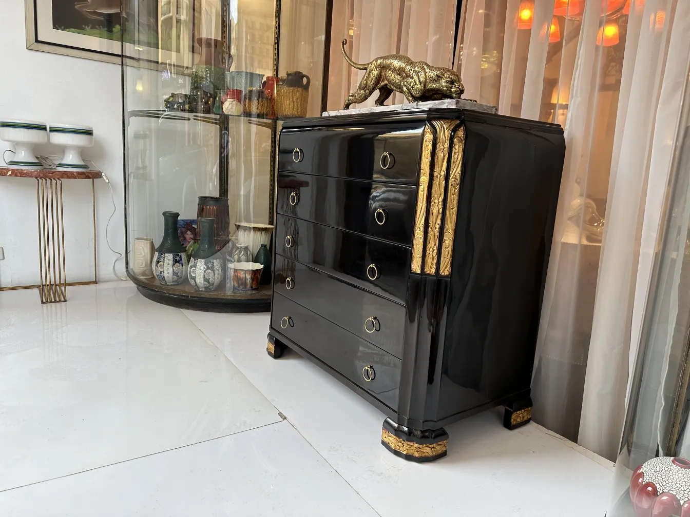 Commode ancienne noire avec des accents dorés et décoration de lion