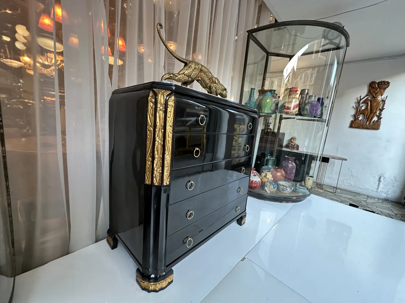 Commode ancienne avec un élégant fini noir et doré et des détails décoratifs.