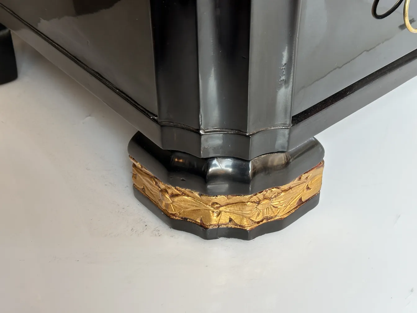 Base de una cómoda antigua con detalles dorados en el acabado.