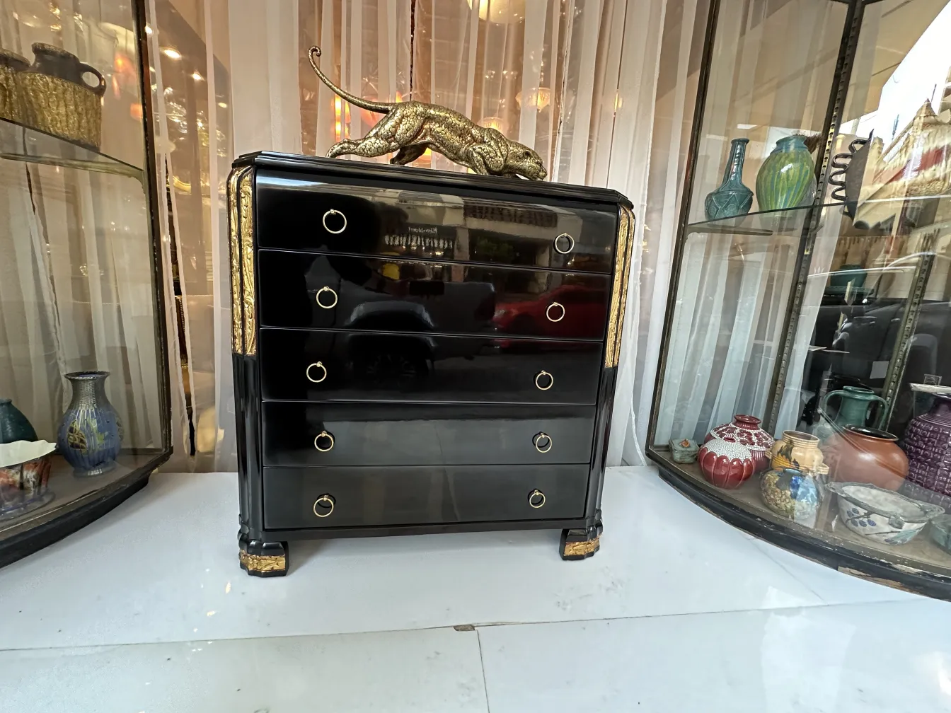 Commode noire ancienne avec accents dorés et félin décoratif