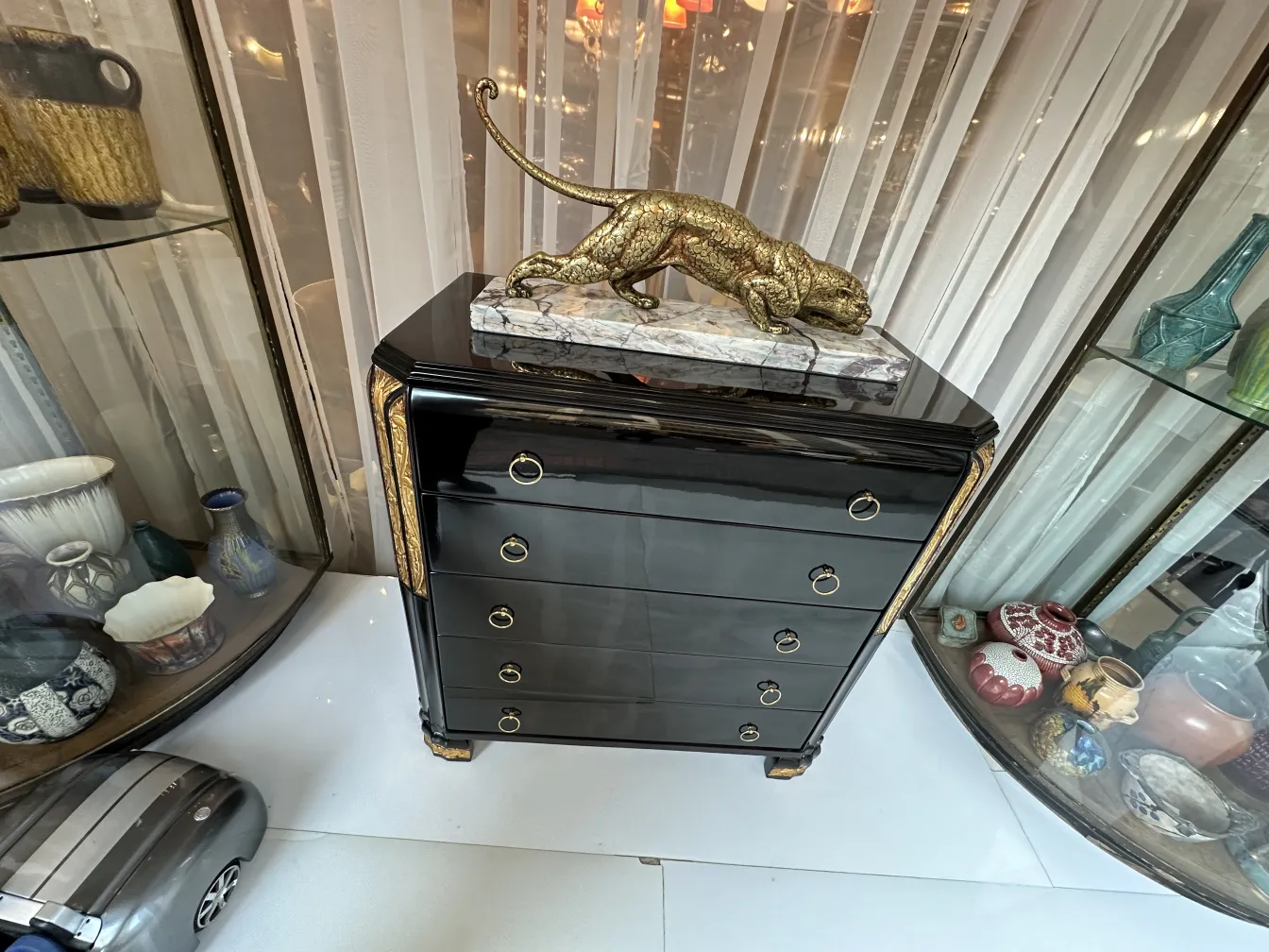 Cómoda antigua negra con adorno de bronce, con fondo de colecciones decorativas.