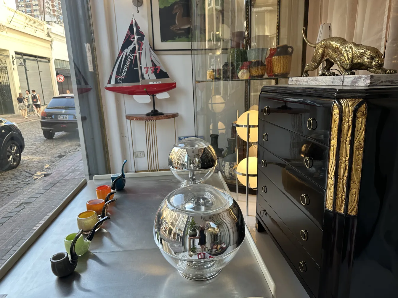Antique black cabinet with golden details and decorative items around it.