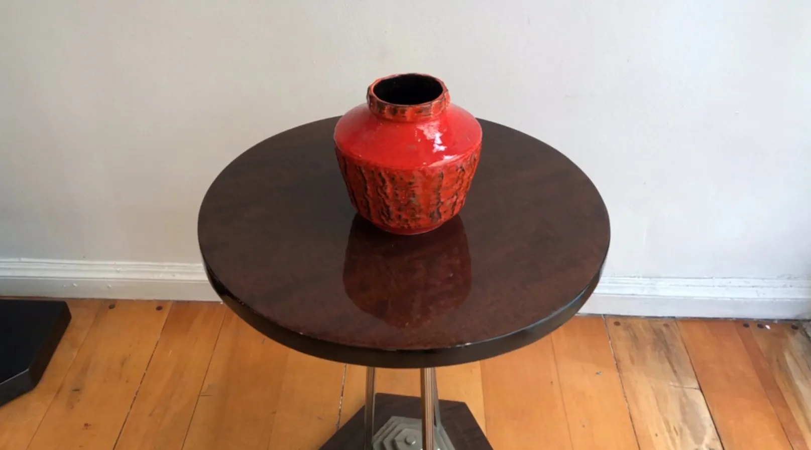 Vase en céramique ancienne de couleur rouge vif sur une table.