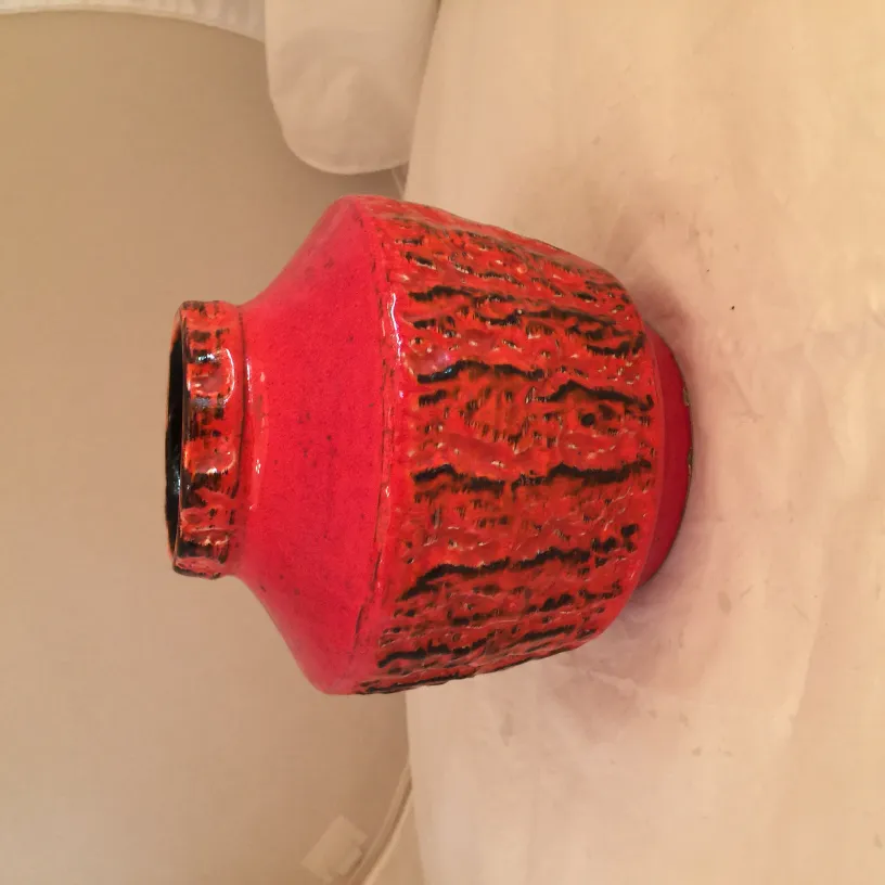 Старая красная керамическая банка с текстурированной поверхностью.