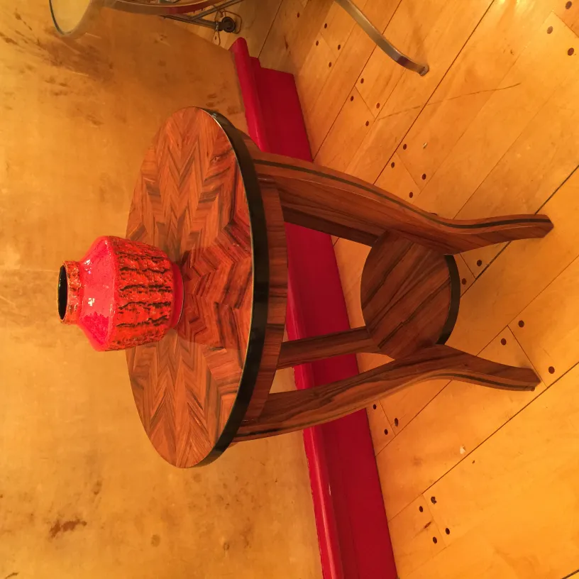 Vase rouge en céramique sur une table en bois foncé.