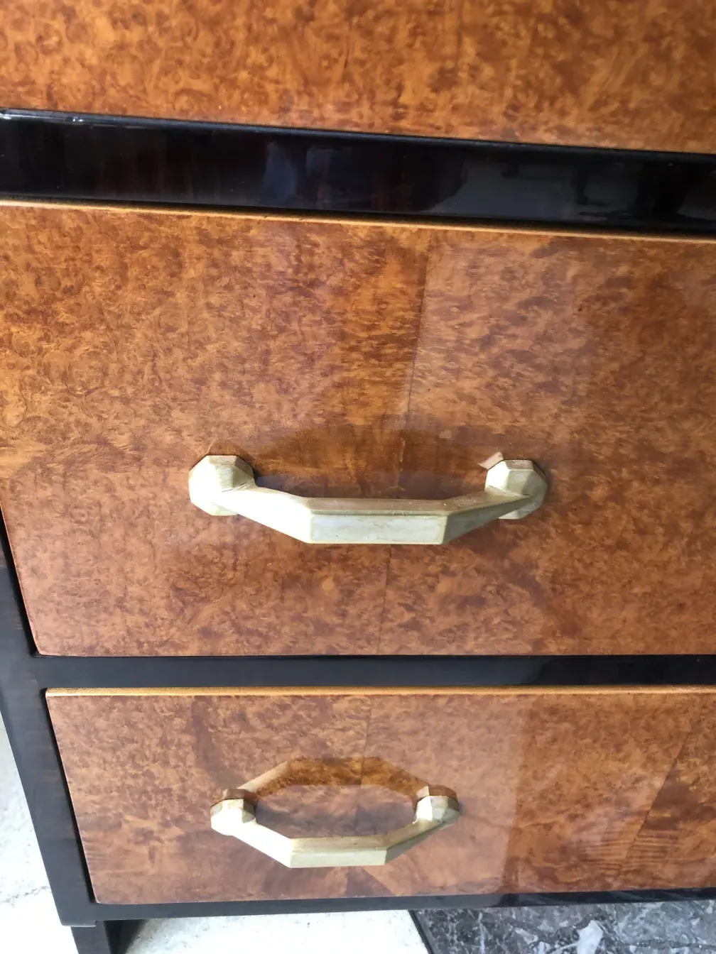 Commode ancienne avec finition brillante et poignées dorées.