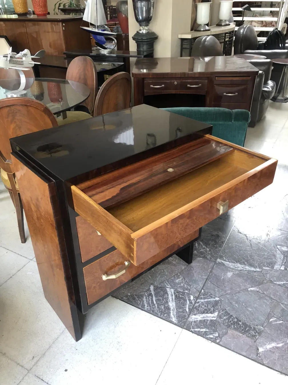 Comoda antigua de madera con detalles trabajados y tiradores dorados, en un entorno de muebles elegantes.
