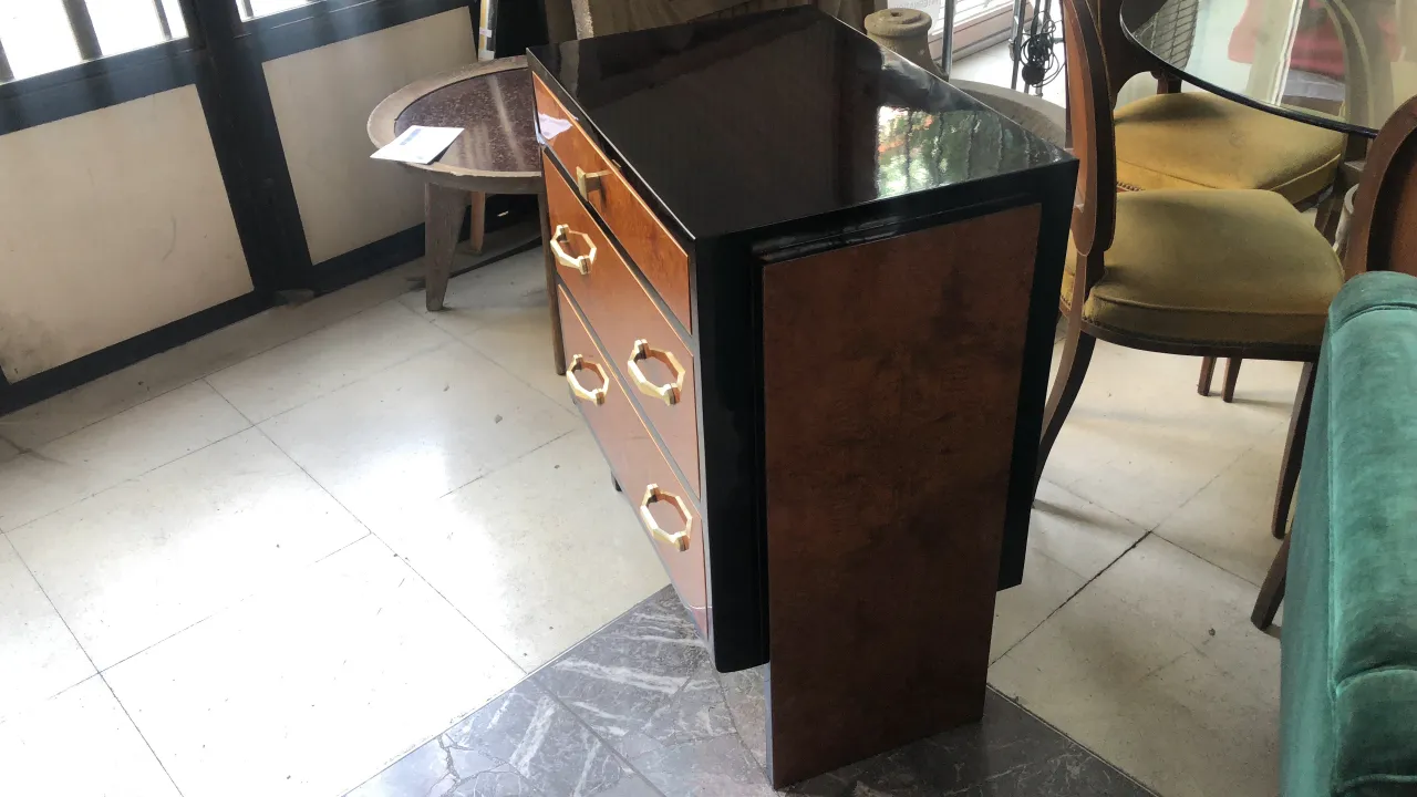 Cassetto antico in legno con tre cassetti e gambe, ambientato in un contesto accogliente.