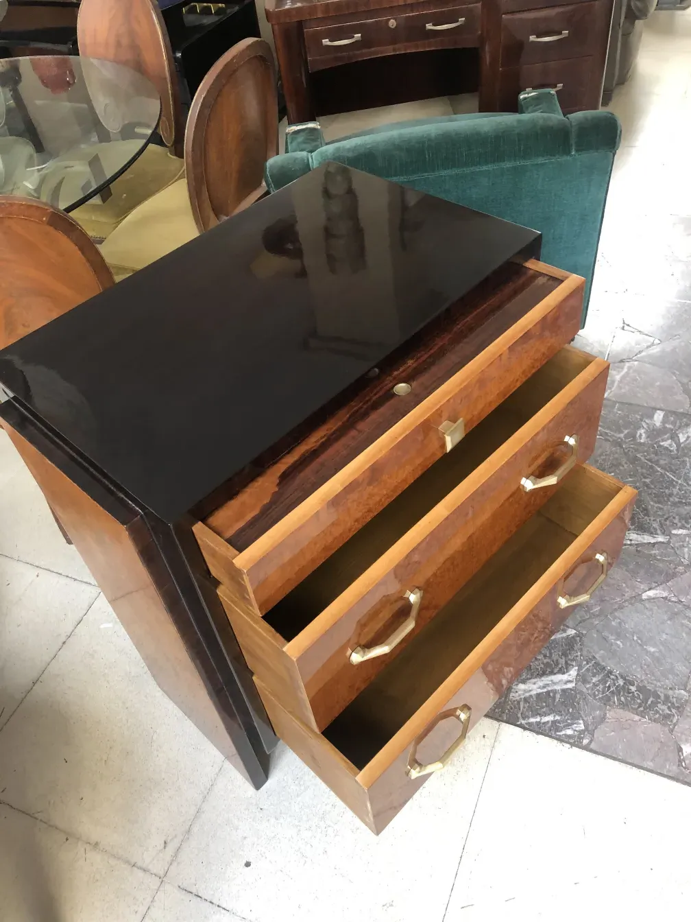 Commode ancienne en bois avec trois tiroirs et poignées dorées dans un cadre accueillant.