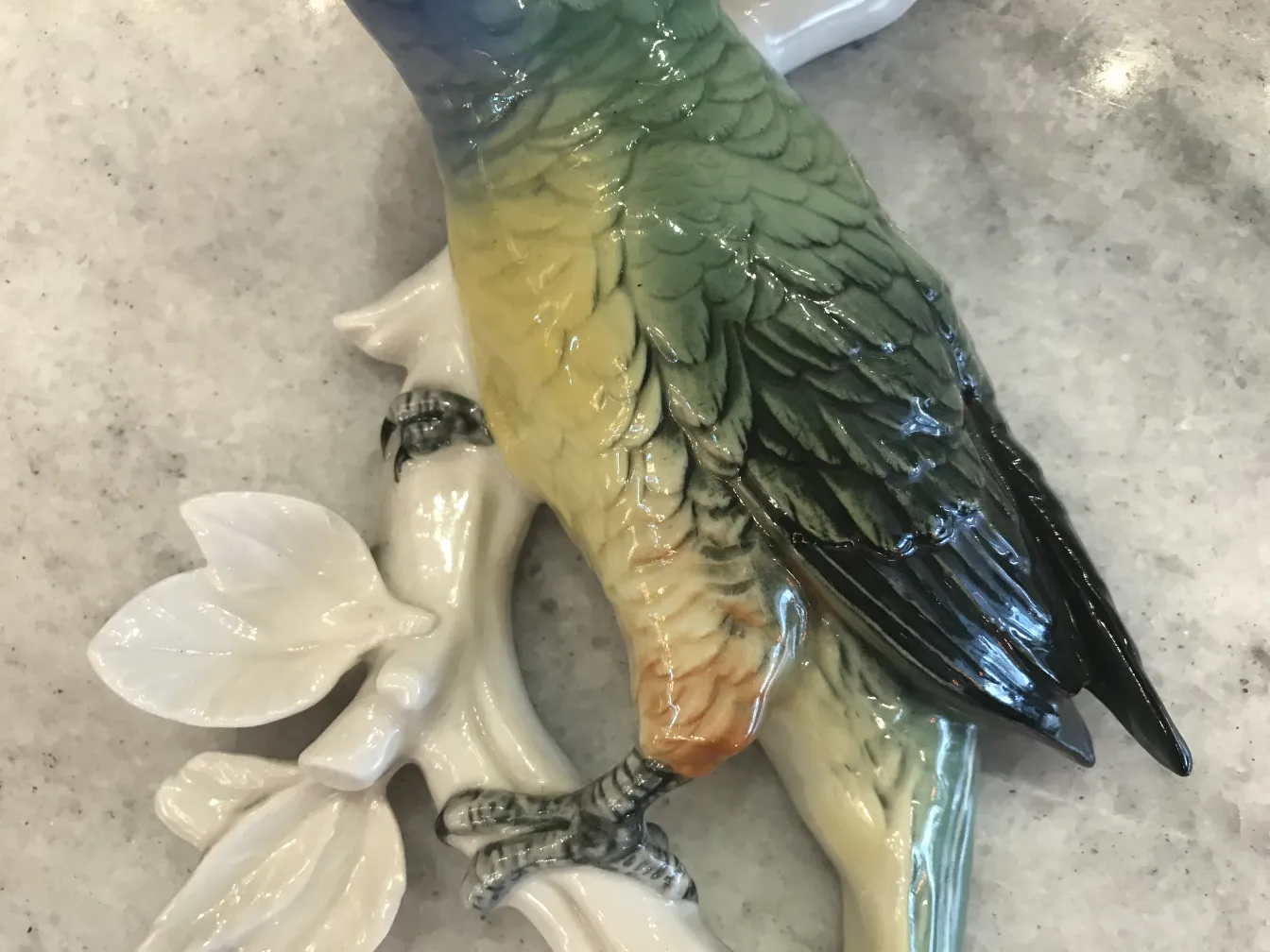 Figurina di uccello in ceramica antica colorata su un ramo