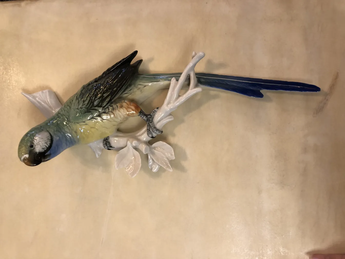 Uccello in ceramica antico su ramo bianco con foglie