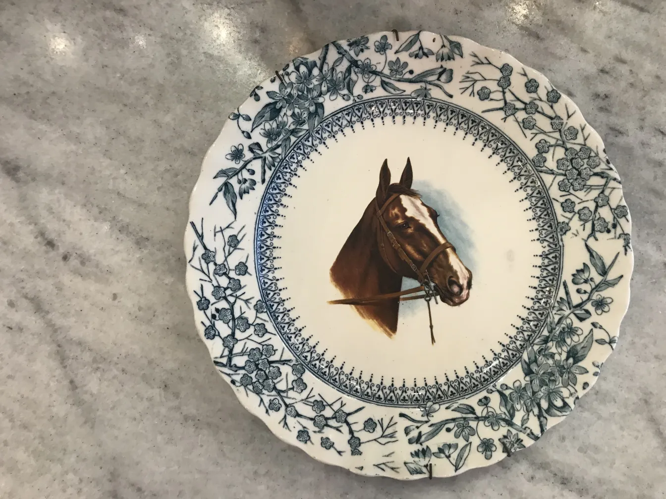 Antique plate featuring a horse design and blue flowers.
