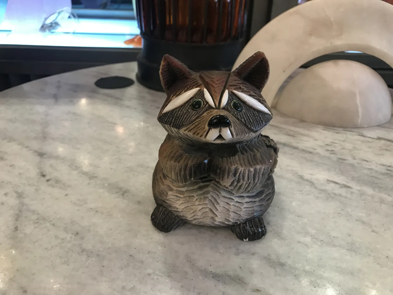 escultura cerâmica antiga em forma de guaxinim, detalhes em cinza e branco, em uma mesa