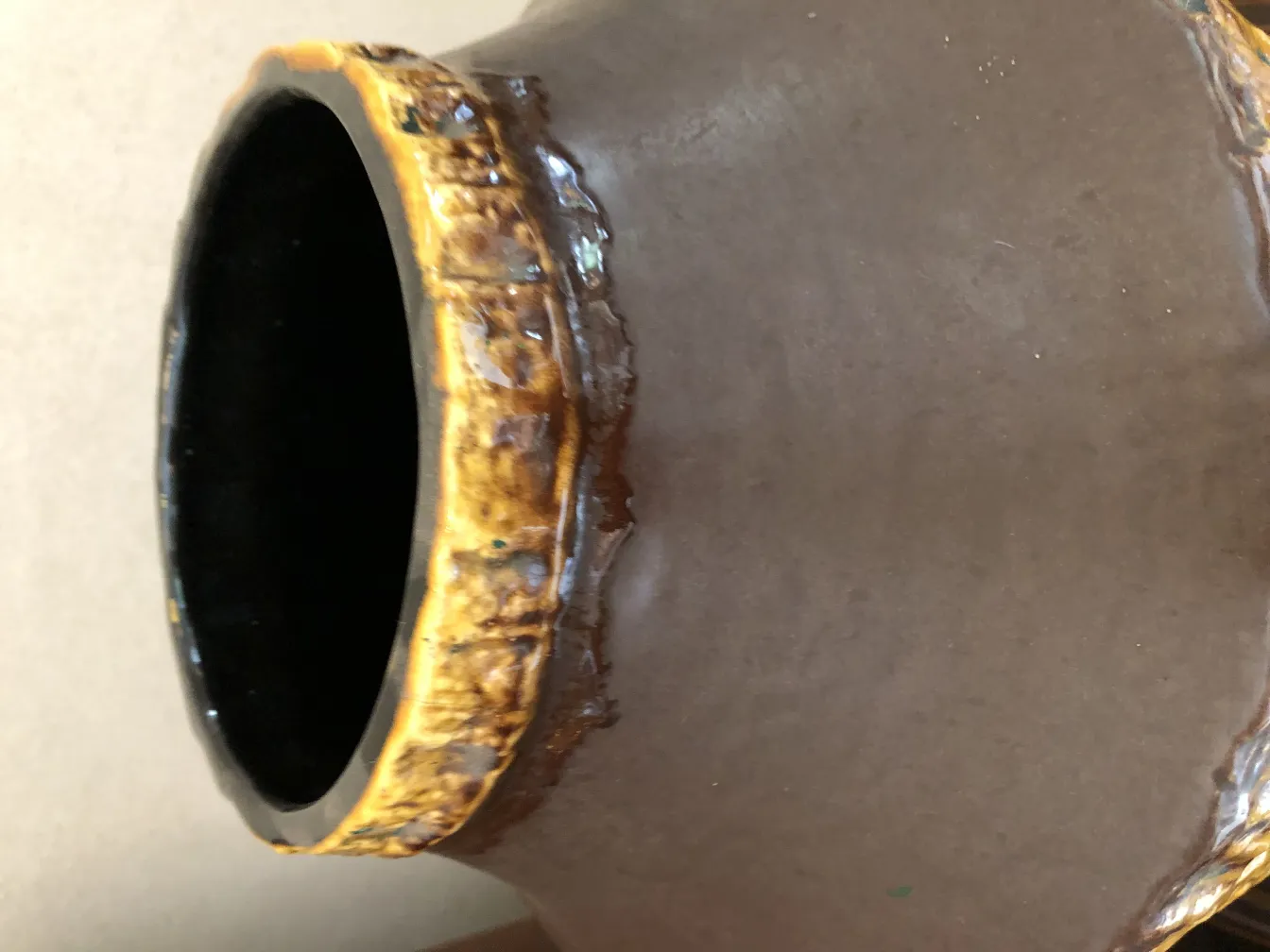 Antique ceramic vase with shiny black interior and golden decoration.
