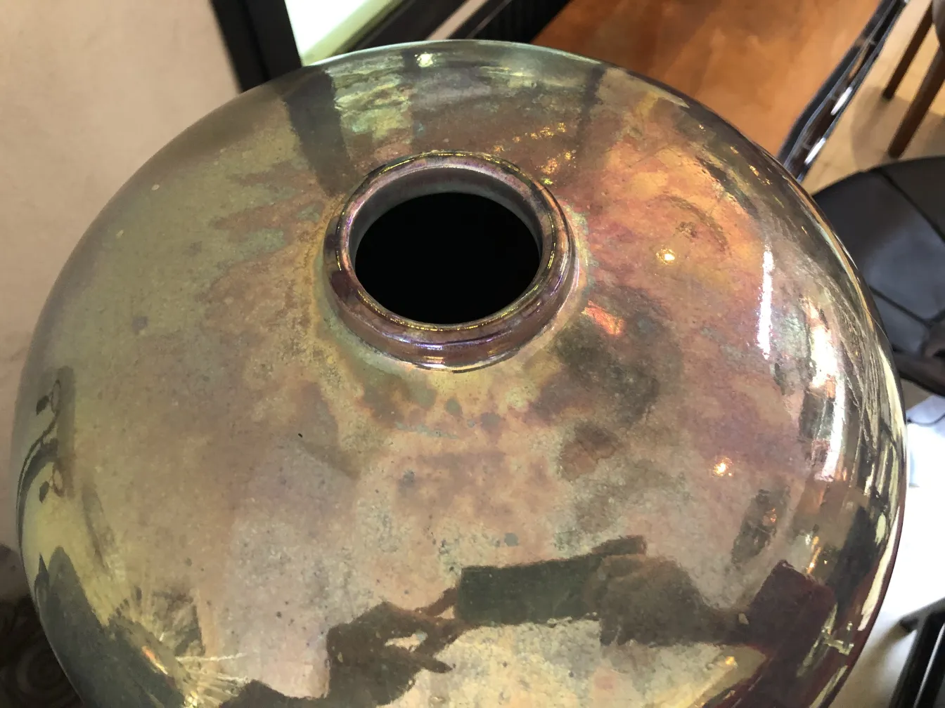 Vue de dessus d'un vase en céramique antique brillant avec des reflets lumineux.