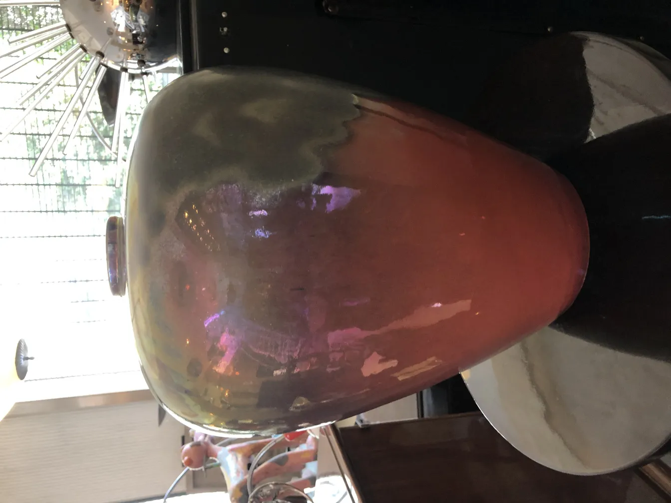 Vaso de cerâmica antiga com tons iridescentes em um ambiente decorativo.