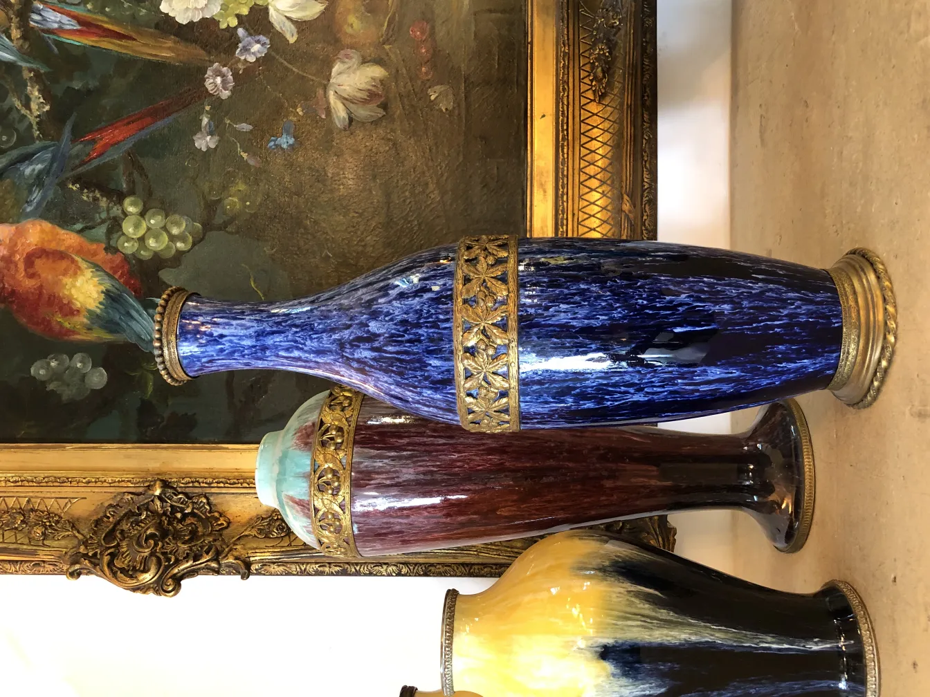 Vases en céramique ancienne décorative de différentes couleurs devant une fresque florale