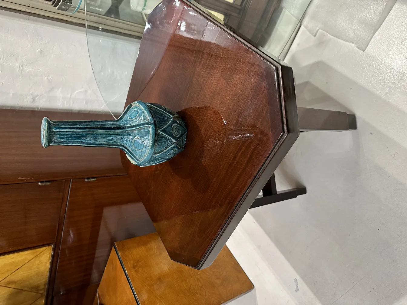 Jarrón de cerámica antigua con diseño azul brillante, sobre una mesa de madera.