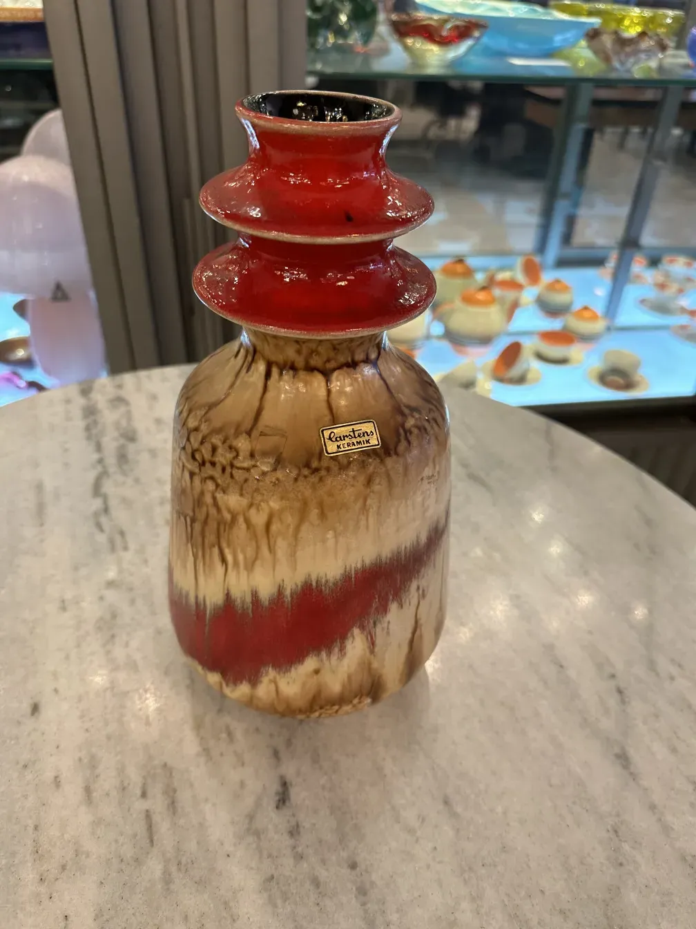 Antique ceramic vase with red and beige designs.