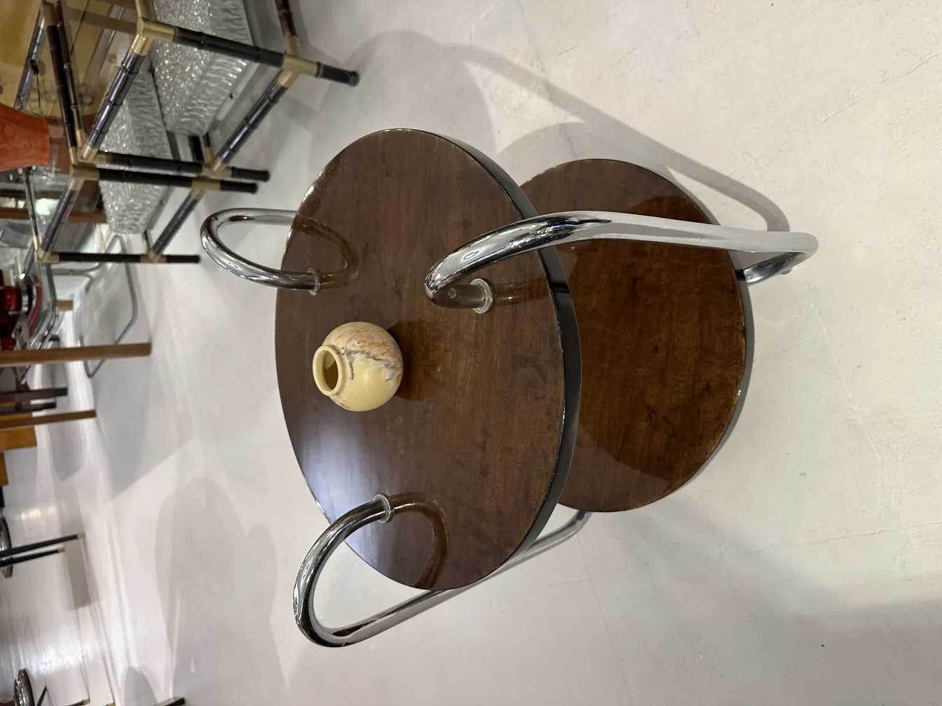 Jarrón de cerámica antigua sobre mesa de madera con patas cromadas.