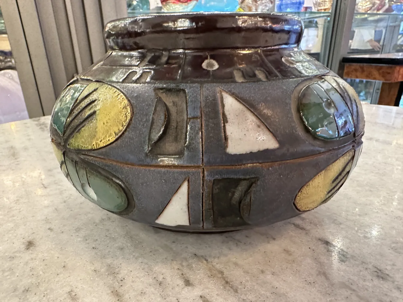 Vaso di ceramica antica decorato con motivi colorati su sfondo grigio chiaro.