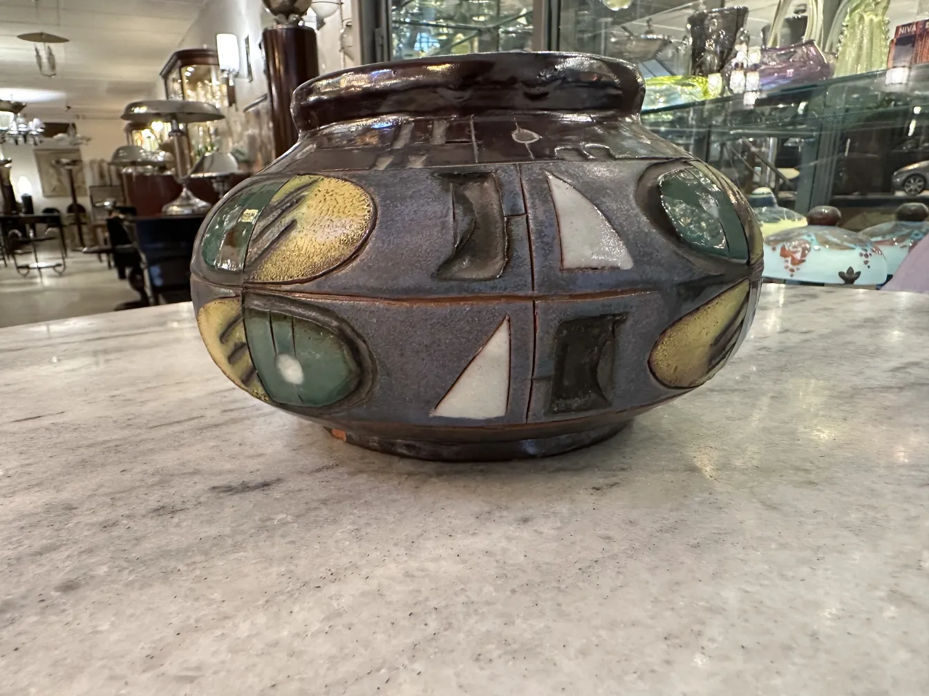 Vaso de cerâmica antiga com decorações coloridas em verde e amarelo.