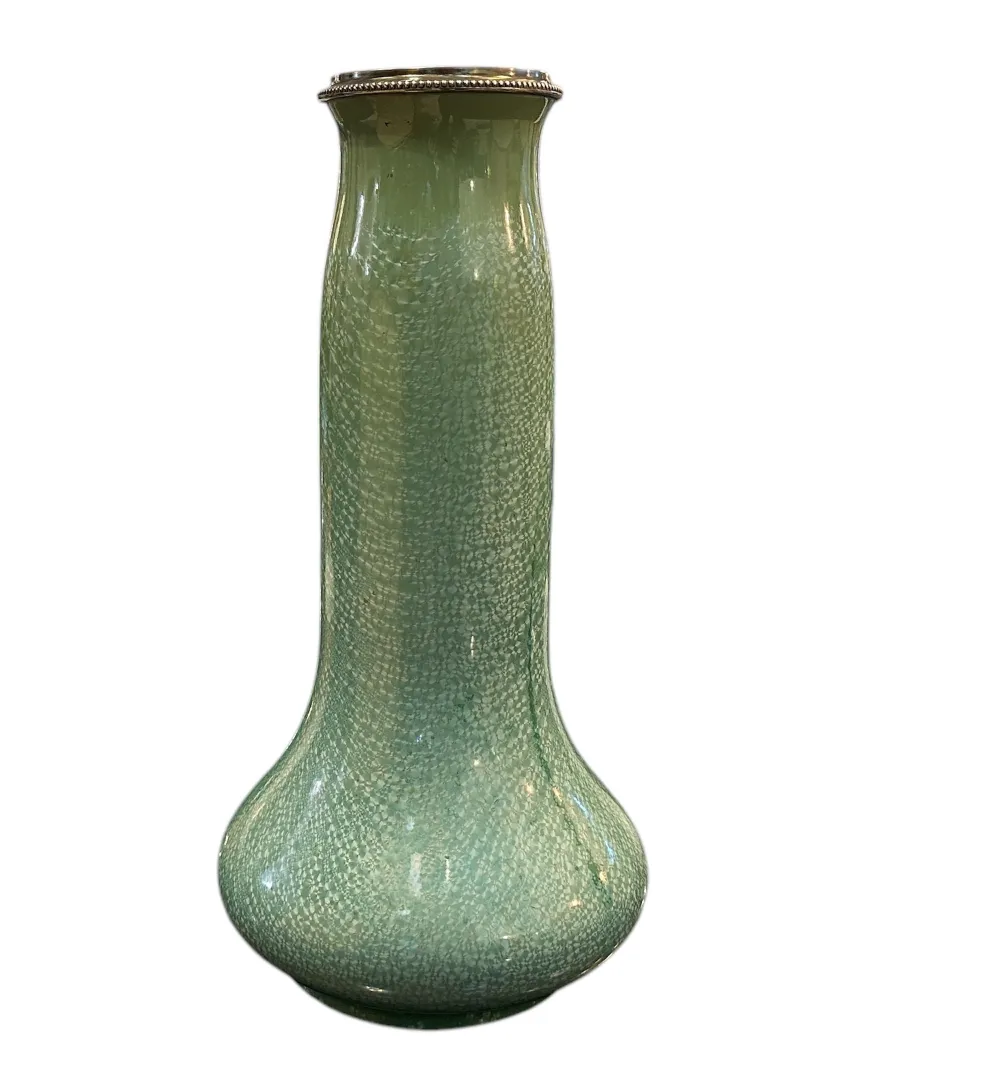 Vase en céramique verte avec texture sur un fond neutre.