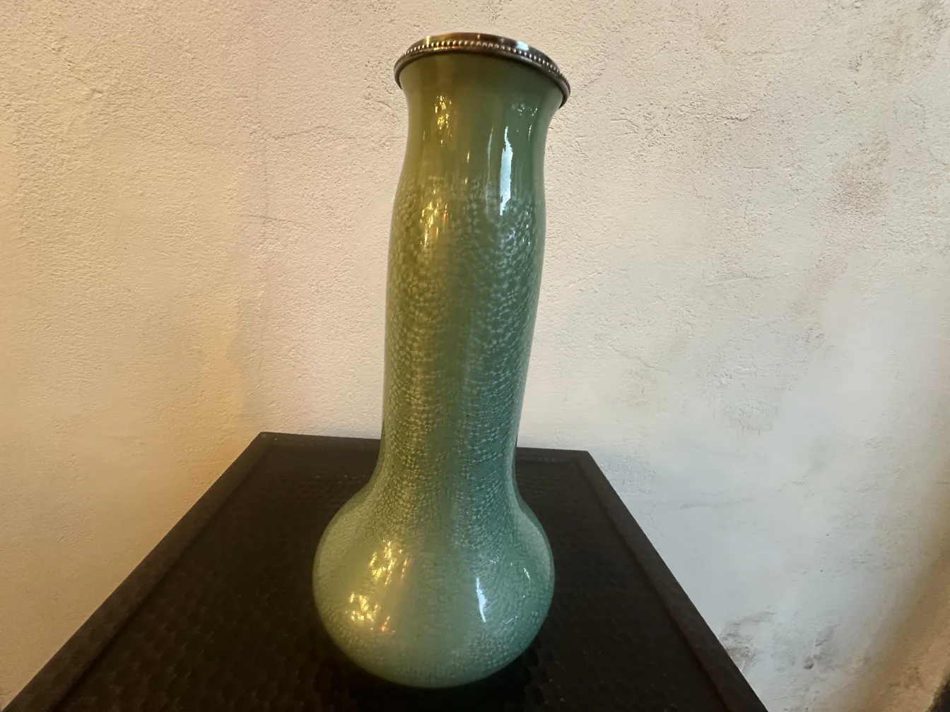 Vaso verde in ceramica antica con dettagli testurizzati.