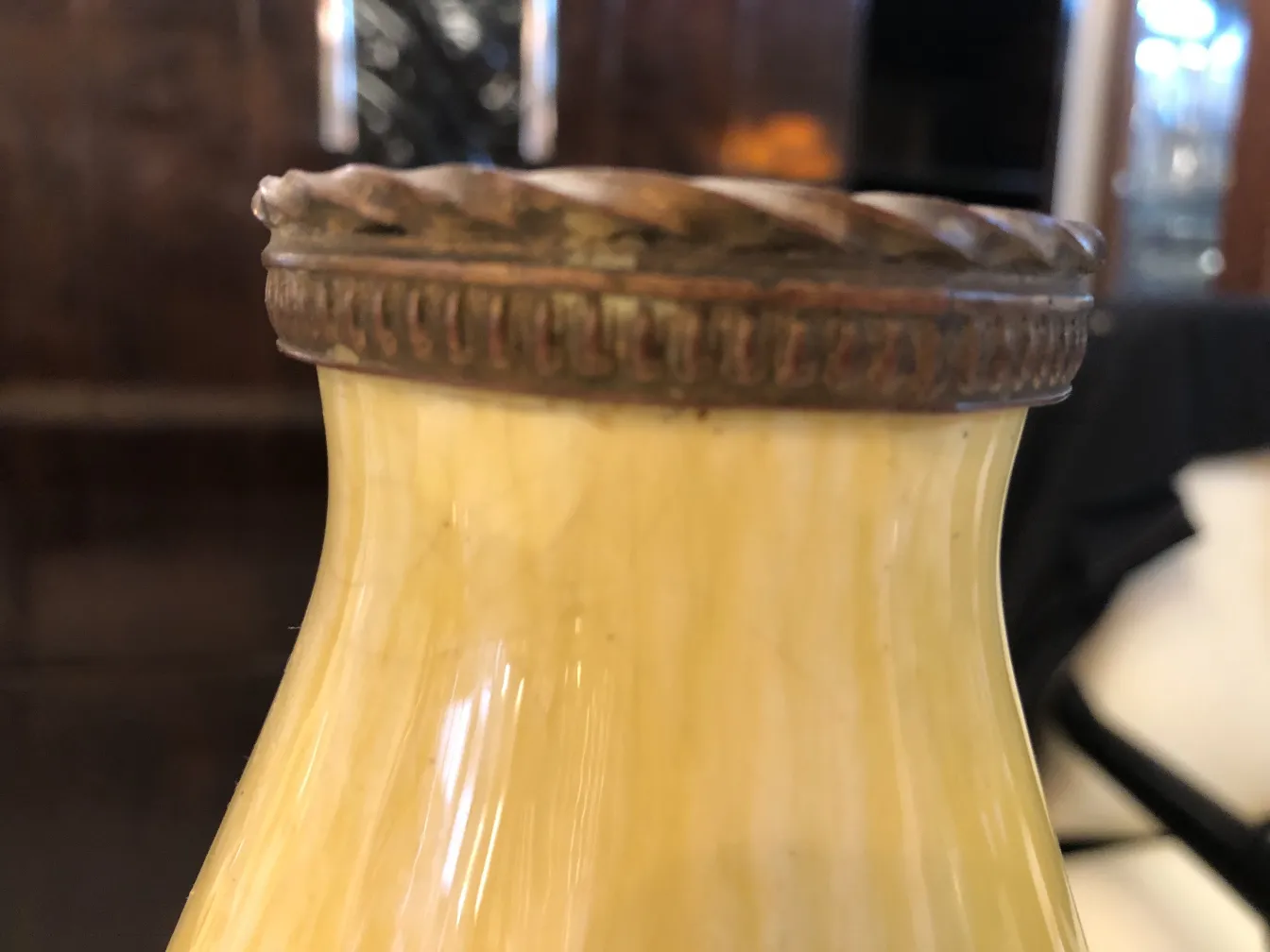 Botella antigua de cerámica con tapa decorativa y curvilínea, de Boch frères, con un color amarillo suave.