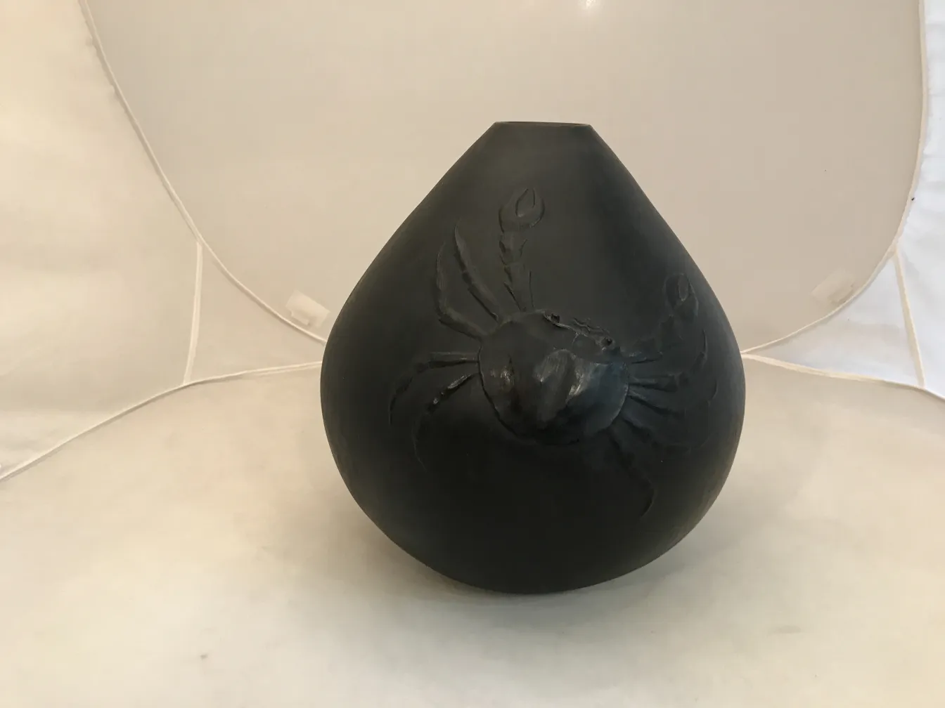 Vaso de cerâmica antiga com relevo de aranha, fundo branco