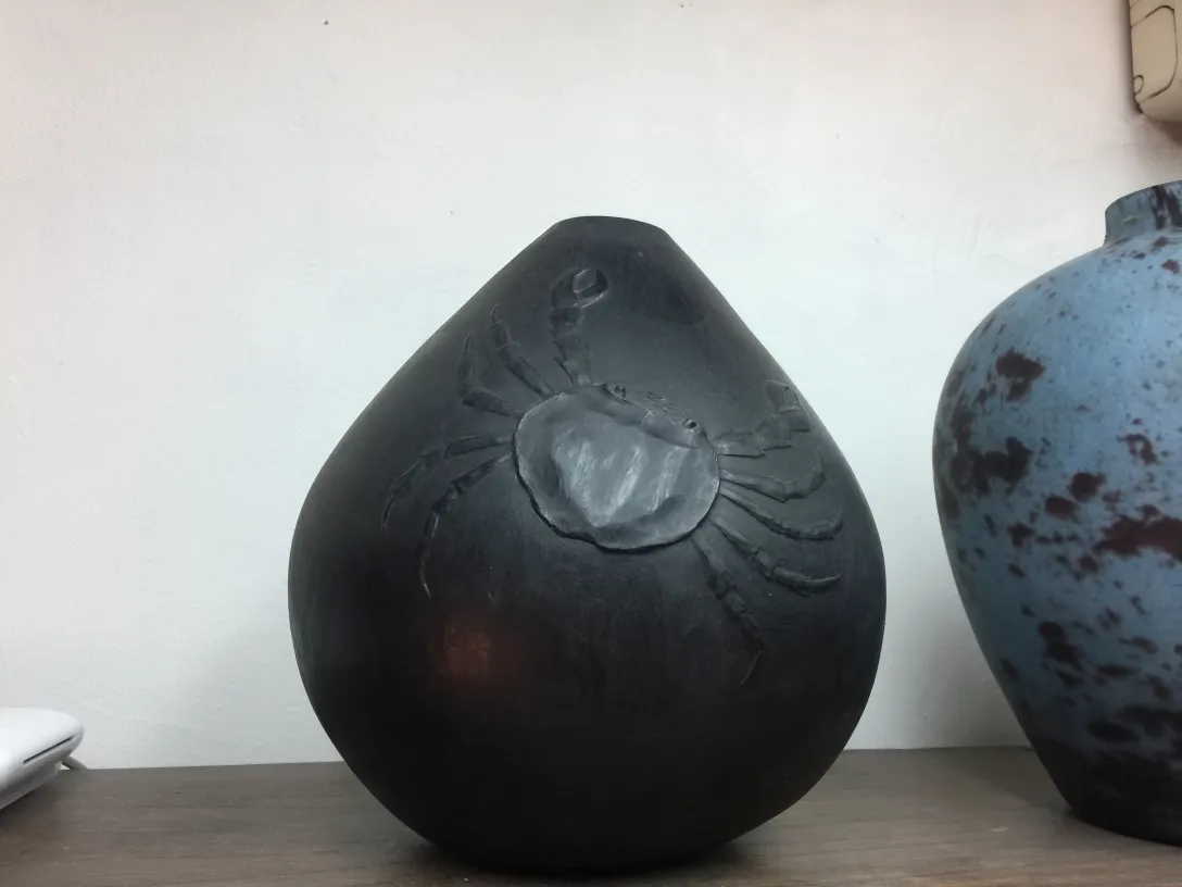 Vaso in ceramica nera con design di granchio, in un ambiente elegante.