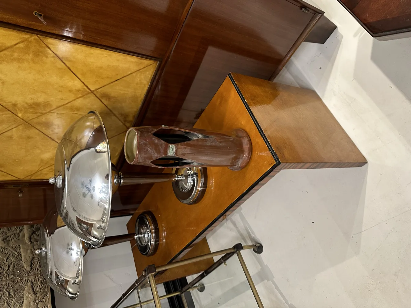 Cerâmica antiga decorativa com detalhes estilizados em um ambiente elegante, junto a objetos metálicos.