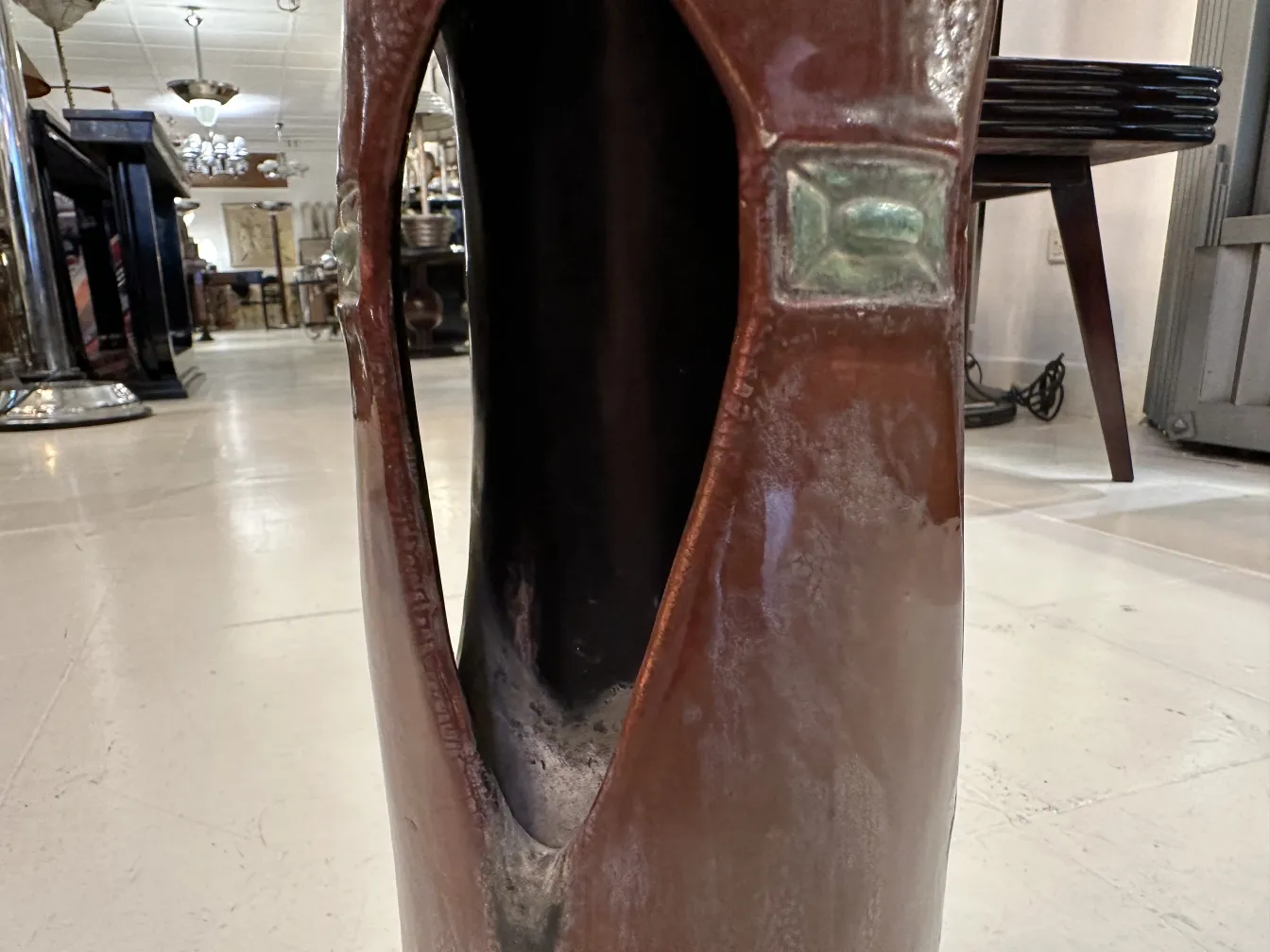 Antique ceramic vase with an opening and decorative elements in a classic style environment.