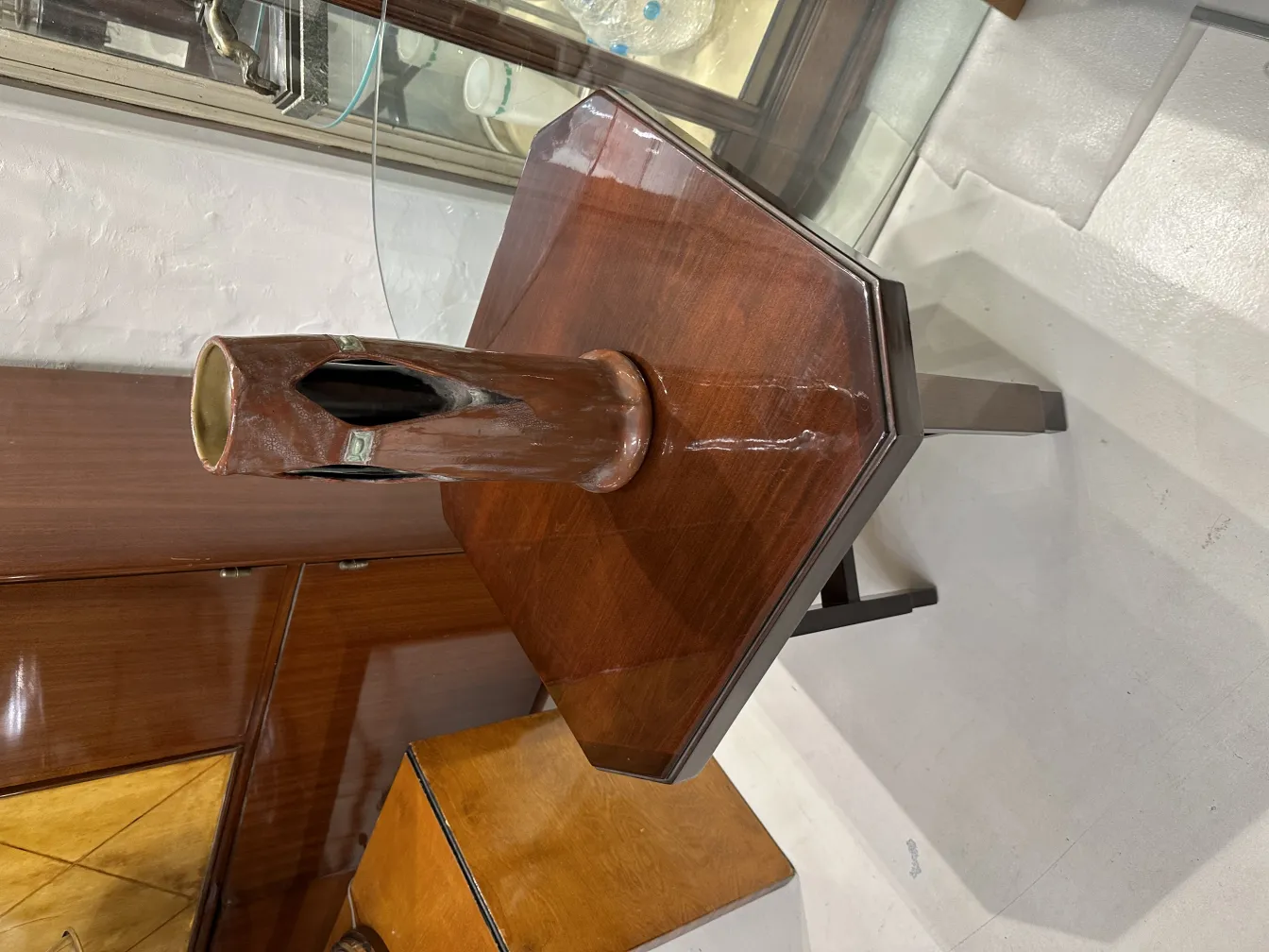 Jarrón de cerámica antigua en un ambiente elegante, con un fondo de muebles de madera