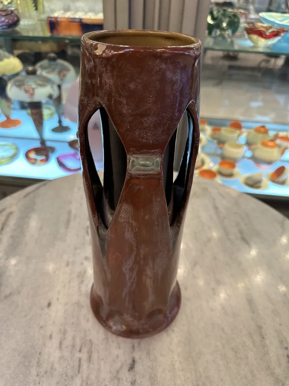 Antike Keramikvase mit markantem kurvigen Design in braunen Tönen, dekoratives Umfeld.