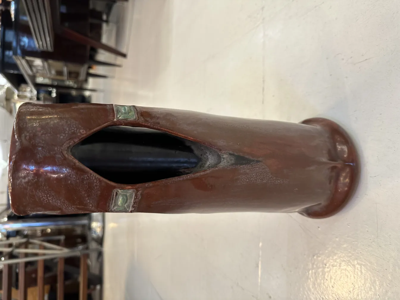 Vaso de cerâmica antiga com detalhes elaborados e cor marrom escuro.