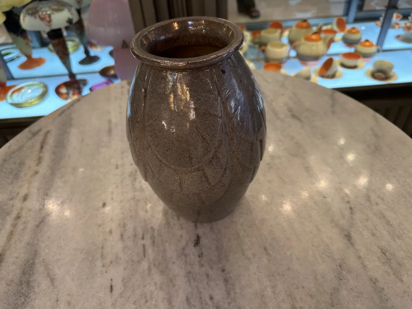 Vaso de cerámica antigua con decoración texturizada, complementado con un ambiente elegante.